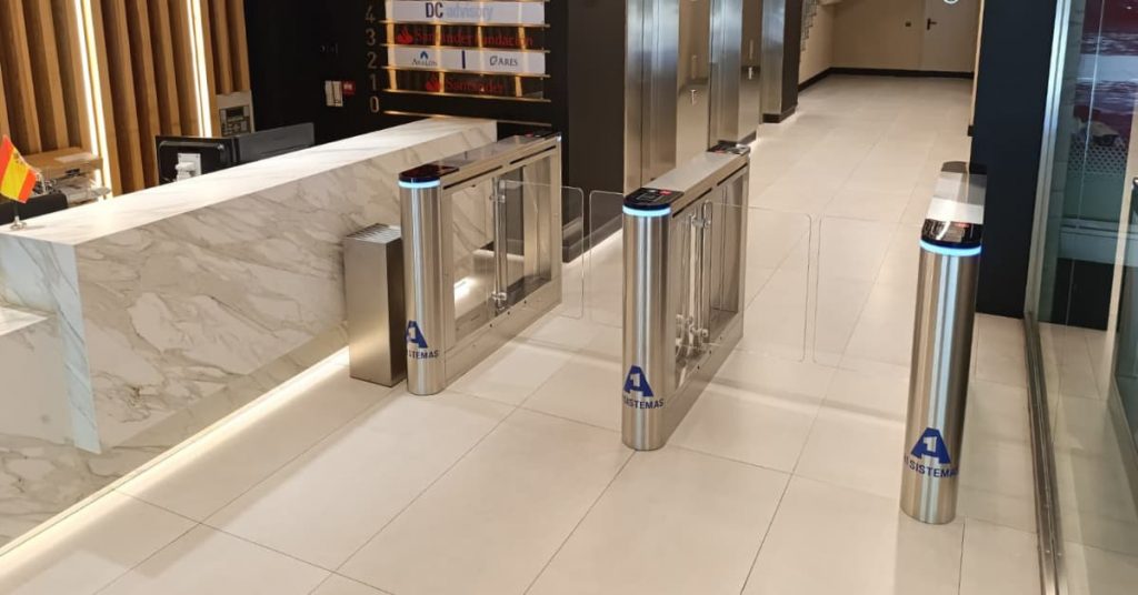 Sistema de control de accesos con tornos motorizados instalado en el acceso de un edificio de oficinas.