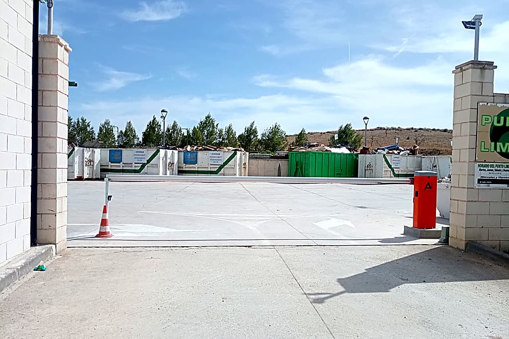 Barrera automática de control de acceso de vehículos instalada en la entrada de un punto limpio.